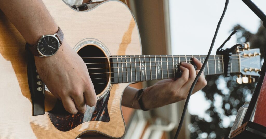 スタイリッシュなデザインのチューナーを手にするギタリスト。機能より見た目を重視して失敗する例。